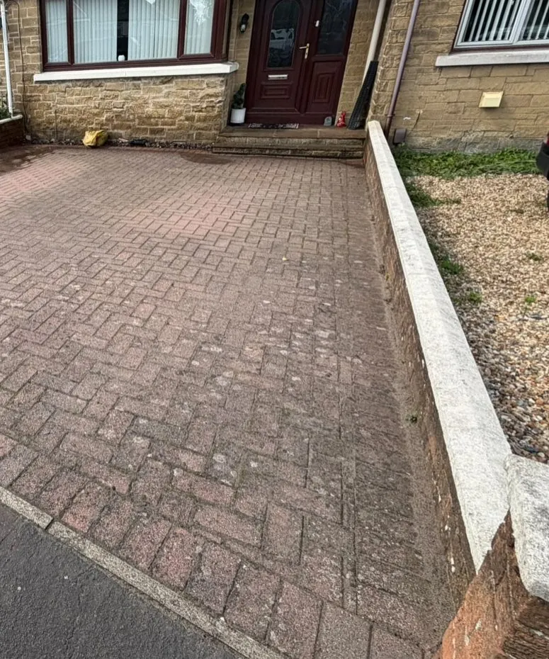 Herringbone block paving driveway on a terraced street, dull and stained before cleaning